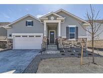 Charming gray home featuring stone accents, a two-car garage and a landscaped front yard at 8946 S Rome Ct, Aurora, CO 80016