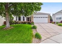 Charming home with a large tree in the front yard and a two-car garage with stone accents at 5656 S Sicily Ct, Aurora, CO 80015