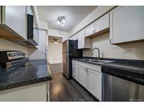 Kitchen featuring white cabinets, stainless steel appliances, and black countertops at 4569 S Lowell Blvd # B, Denver, CO 80236