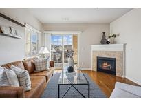 Bright living room with a cozy fireplace and sliding glass doors to a balcony at 725 Elmhurst Dr # 306, Highlands Ranch, CO 80129
