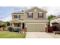Charming two-story home featuring red shutters, green siding, a two-car garage, and a beautifully landscaped front yard at 6385 S Nelson Way, Littleton, CO 80127