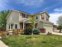 Charming two-story home with a well-manicured lawn, attached two car garage, and lovely red shutters at 6385 S Nelson Way, Littleton, CO 80127