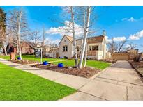 Charming home with manicured lawn, blue flowerpots and mature trees on a sunny day at 5030 W 33Rd Ave, Denver, CO 80212