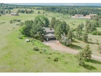 Expansive property featuring lush greenery, mature trees, and a charming home with a spacious driveway and attached garage at 9212 Tanglewood Rd, Franktown, CO 80116