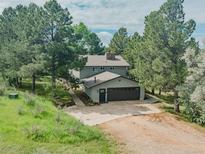 Two-story home with a gray exterior, attached garage and mature trees on a sunny day at 9212 Tanglewood Rd, Franktown, CO 80116