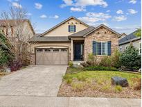 Charming home featuring a stone facade, well-manicured lawn, and attached two-car garage at 22310 E Chenango Dr, Aurora, CO 80015