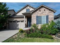 Charming home featuring a stone facade, two-car garage, landscaped yard, and inviting blue front door at 22310 E Chenango Dr, Aurora, CO 80015