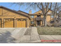 Inviting townhome featuring a two-car garage and a charming exterior with wood paneling and a stone chimney at 9088 W 88Th Cir, Westminster, CO 80021