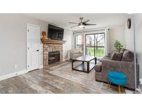 Cozy living room features a stone fireplace, a ceiling fan, and a sliding glass door to the balcony at 8666 Decatur St # 254, Westminster, CO 80031