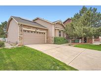 Charming home featuring a stone-accented facade, well-maintained lawn, and a two-car garage at 23882 E Alabama Dr, Aurora, CO 80018