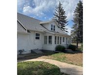 Charming home with a white exterior, gray roof, sunroom and lush landscaping under a beautiful blue sky at 5195 Allison St, Arvada, CO 80002