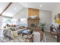 Spacious living room featuring a brick fireplace, vaulted ceilings, and plenty of natural light at 5195 Allison St, Arvada, CO 80002