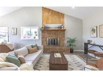 Bright living room featuring a brick fireplace, wood accent wall, and stylish decor at 5195 Allison St, Arvada, CO 80002