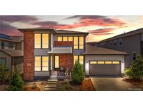 Beautiful two-story home with a brick and gray exterior and a manicured front yard at sunset at 9340 Mount Jackson St, Littleton, CO 80125