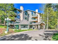 Inviting condo complex with stone accents and a covered entryway surrounded by lush landscaping at 31819 Rocky Village Dr # 418, Evergreen, CO 80439