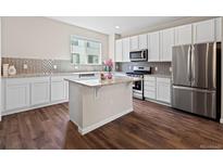 Modern kitchen with white cabinetry, stainless steel appliances, granite countertops, and center island at 1330 Independence St # 2, Lakewood, CO 80215