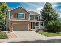 Charming two-story home with a brick and siding exterior, complemented by a well-maintained lawn and driveway at 14170 W Warren Dr, Lakewood, CO 80228