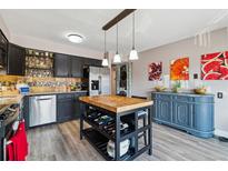 Bright kitchen with stainless steel appliances, butcher block island, and adjacent dining and bar area at 6495 E Happy Canyon Rd # 163, Denver, CO 80237