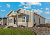 One-story home with light beige siding, a covered porch, and landscaping at 2958 Oxley St, Strasburg, CO 80136