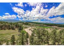 Scenic aerial view of wooded property with athletic fields and mountain views under a vibrant blue sky at 10550 Highway 73, Conifer, CO 80433