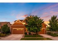 Charming two-story home featuring stone accents and a two-car garage, nestled under a vibrant sunset sky at 8782 S Wenatchee Ct, Aurora, CO 80016