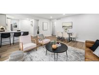 Bright living room boasts modern furniture, wood floors, and a stylish rug, open to kitchen bar at 5491 Lowell Blvd, Denver, CO 80221