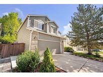 Charming two-story home features a well-manicured lawn and attached two-car garage, with tan siding and brick accents at 4857 Tarcoola Ln, Highlands Ranch, CO 80130