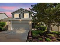 Two-story home featuring brick accents, two-car garage, and a mature shade tree at 4857 Tarcoola Ln, Highlands Ranch, CO 80130