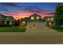 Charming two-story home boasts a three-car garage, lush lawn, and well-maintained landscaping at dusk at 9884 Sydney Ln, Highlands Ranch, CO 80130