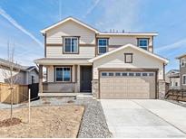 Charming two-story home featuring a covered porch, attached two-car garage, and neutral-toned siding with brown trim at 9702 Cathay St, Commerce City, CO 80022