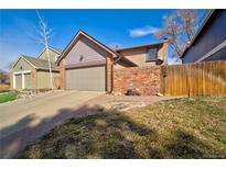 Cozy home featuring a two-car garage and a charming brick wall creating a private front yard space at 8737 Garrison Ct, Arvada, CO 80005