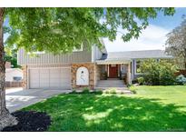Charming home featuring a manicured lawn, beautiful brickwork, and lovely front yard landscaping at 6474 W Canyon Ave, Littleton, CO 80128