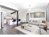 Bright, open-concept living room featuring modern decor, hardwood floors, and seamlessly connected kitchen with bar seating at 8367 S Reed St # A3, Littleton, CO 80128