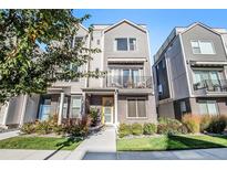 Attractive townhouse features a yellow front door, a small balcony and manicured landscaping at 888 S Valentia St # 101, Denver, CO 80247