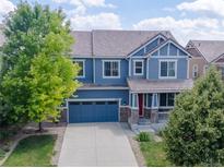 Charming blue two-story home with a well-manicured front yard, covered porch, and attached two-car garage at 3216 Yale Dr, Broomfield, CO 80023
