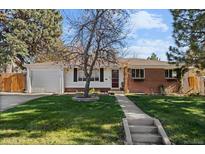 Brick ranch house with attached garage and landscaped yard at 6524 Teller St, Arvada, CO 80003