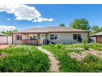 Charming single-story home featuring a cozy porch and a spacious front yard with lush greenery at 1151 Revere St, Aurora, CO 80011