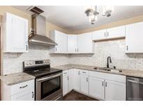Bright kitchen featuring white cabinetry, subway tile backsplash, stainless steel appliances, and granite countertops at 1151 Revere St, Aurora, CO 80011