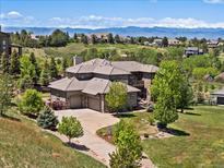 Stunning home featuring a stone facade, three-car garage, mature trees, and mountain views in a scenic neighborhood at 6995 S Ensenada St, Aurora, CO 80016