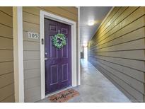 Condo front door with a wreath and welcome mat, leading to the unit's entrance and the hallway at 17442 Nature Walk Trl # 105, Parker, CO 80134