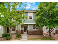Charming two-story townhouse with light green siding, brick accents, and a well-maintained front yard at 19029 E 58Th Ave, Denver, CO 80249