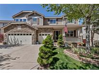 Charming two-story home featuring stone accents, three-car garage, a front porch and a well-manicured lawn at 6345 S Ider Way, Aurora, CO 80016