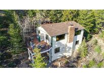 Mountain home featuring a charming deck area with outdoor seating amid lush greenery at 33090 Janelle Cir, Golden, CO 80403