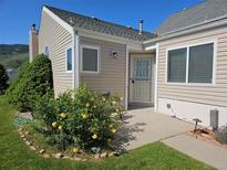 Charming home exterior with a yellow rose bush and well-manicured lawn under a clear blue sky at 535 High Point Dr, Golden, CO 80403
