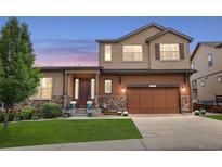 Two-story home with a brown garage door, stone accents, and a well-manicured lawn at 436 Sage Grouse Cir, Castle Rock, CO 80109