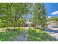 Charming single-story brick home with mature trees, a blue front door, and a well-manicured lawn at 305 Cottonwood Ct, Longmont, CO 80501