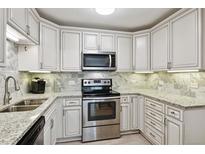 Well-lit kitchen with granite countertops, stainless steel appliances, and white cabinets at 795 S Alton Way # 4C, Denver, CO 80247