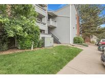 Exterior shot of a light gray condo building with well-maintained landscaping, sidewalk, and partial parking view at 14214 E 1St Dr # B08, Aurora, CO 80011