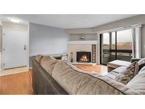 Cozy living room featuring a fireplace, sliding glass door with balcony access, and hardwood flooring at 14214 E 1St Dr # B08, Aurora, CO 80011