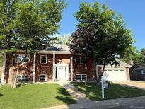 Charming brick home boasts lush landscaping, a pristine lawn, and a welcoming two-car garage at 6842 Garland St, Arvada, CO 80004